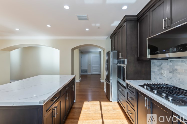 A kitchen with dark cabinets and a marble countertop.