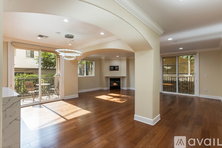 A spacious living room with a fireplace and a balcony with a railing.