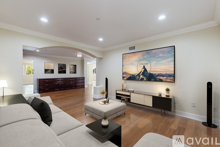 A modern living room with a grey sofa and a large painting on the wall.
