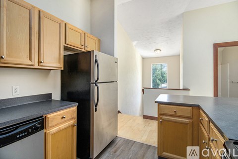 A kitchen with wooden cabinets and a black refrigerator.