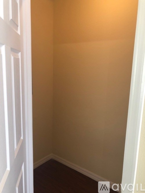 A white door is on the left of a room with beige walls.