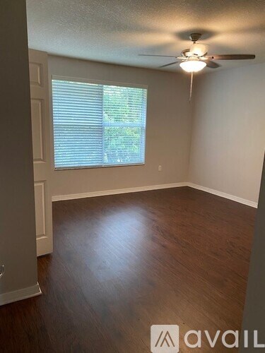A room with a ceiling fan and wooden flooring.