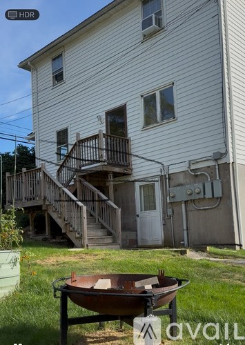 A white house with a wooden deck and a bathtub in front.