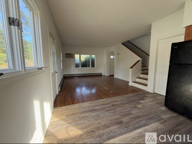 A spacious room with wooden flooring and white walls.