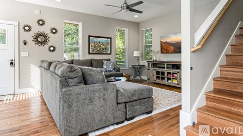 A living room with a grey couch and a wooden staircase.