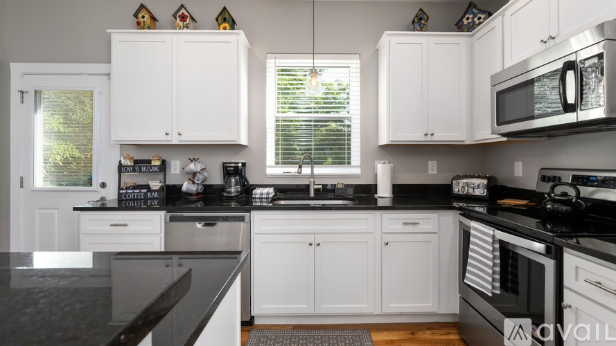 A kitchen with white cabinets and black countertops.
