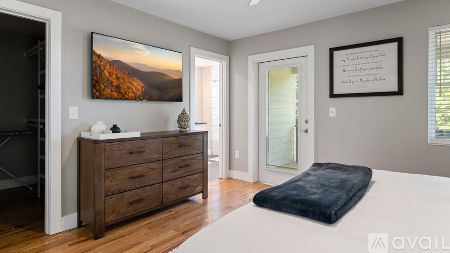 A bedroom with a large bed, a dresser, and a painting on the wall.