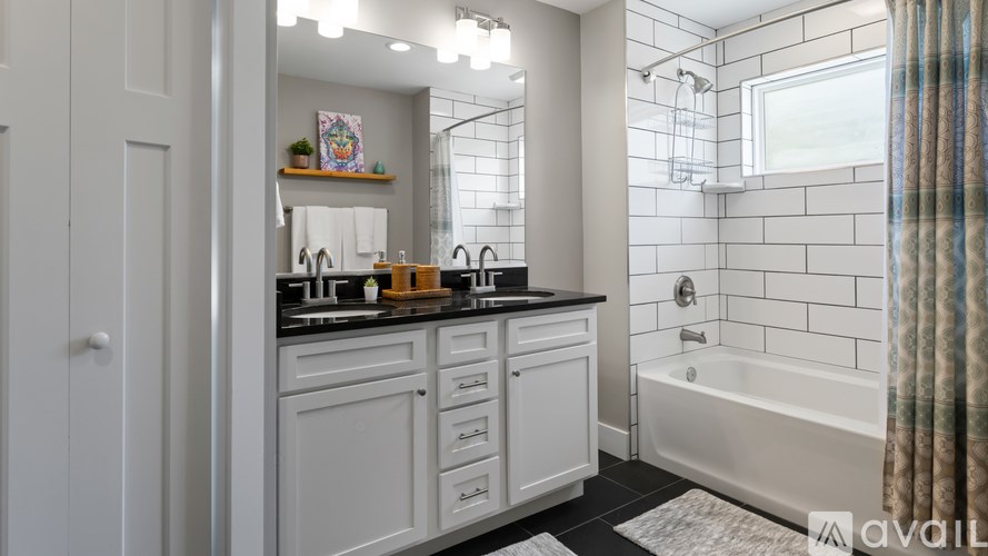 A bathroom with a white tub and a sink with a black counter.