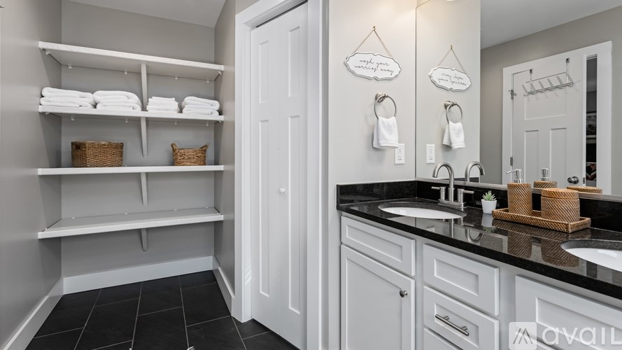 A bathroom with white cabinets and black countertops.