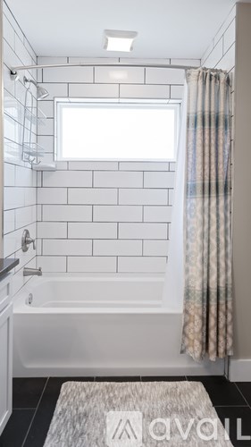 A bathroom with a white tub and a window.