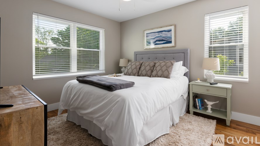 A bedroom with a large bed, a nightstand, and a window with blinds.