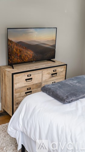A television on a wooden stand with a mountain scene on the screen.