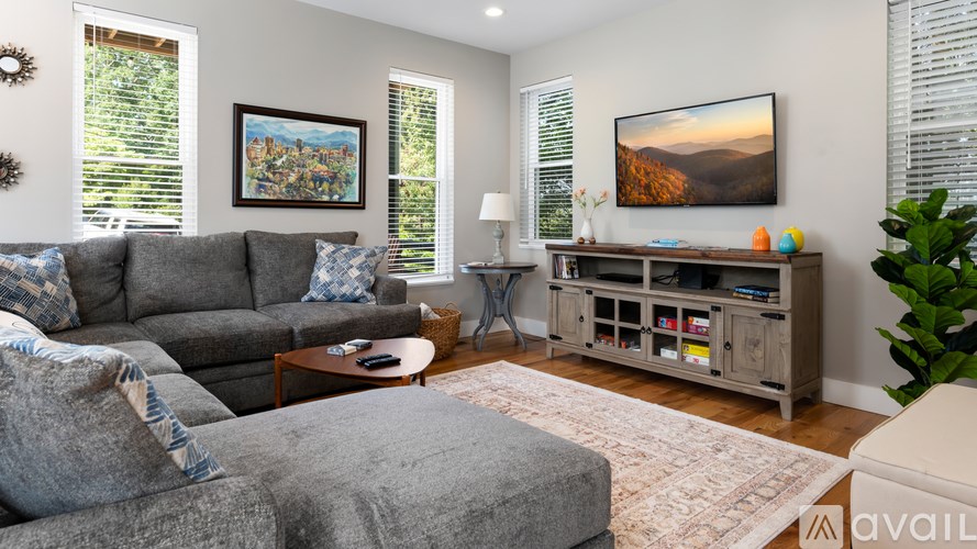 A living room with a grey couch and a painting on the wall.