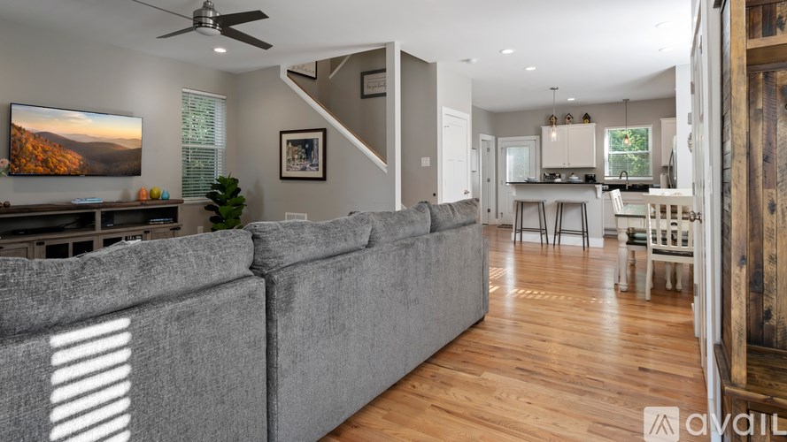 A living room with a grey couch and a painting on the wall.