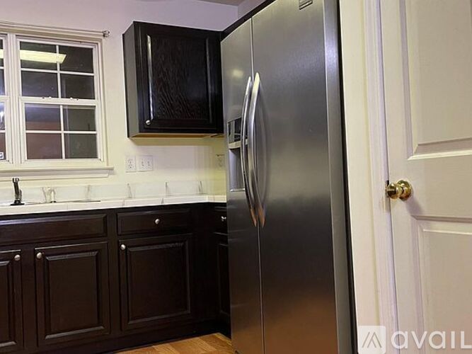 A kitchen with a stainless steel refrigerator and wooden cabinets.