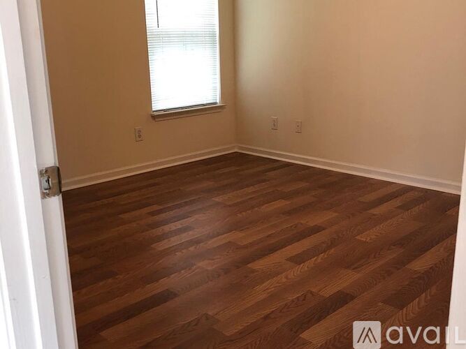 A room with wooden flooring and a window.