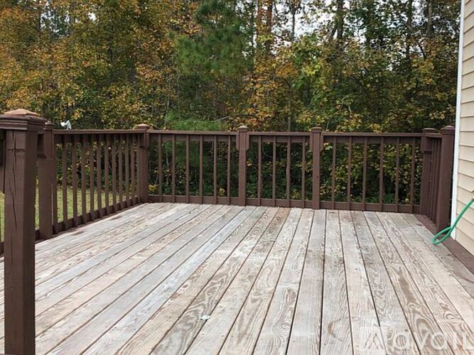 A wooden deck with a railing and trees in the background.