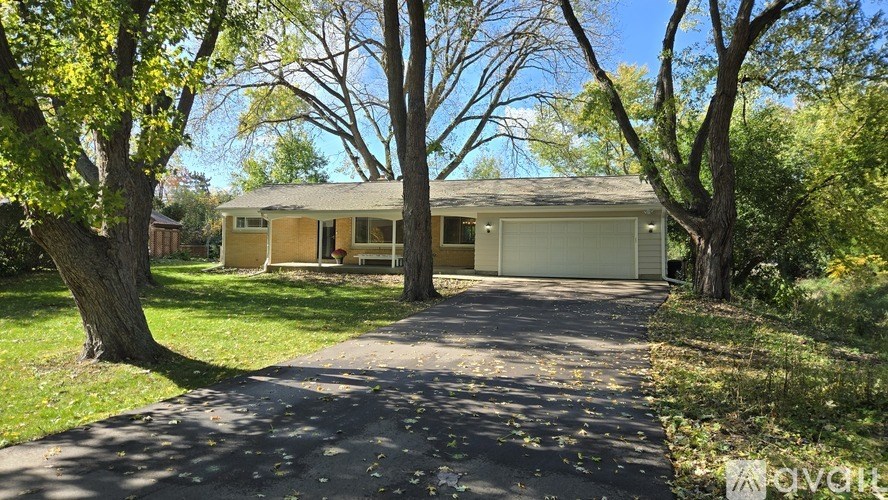A house with a driveway and trees in front of it.