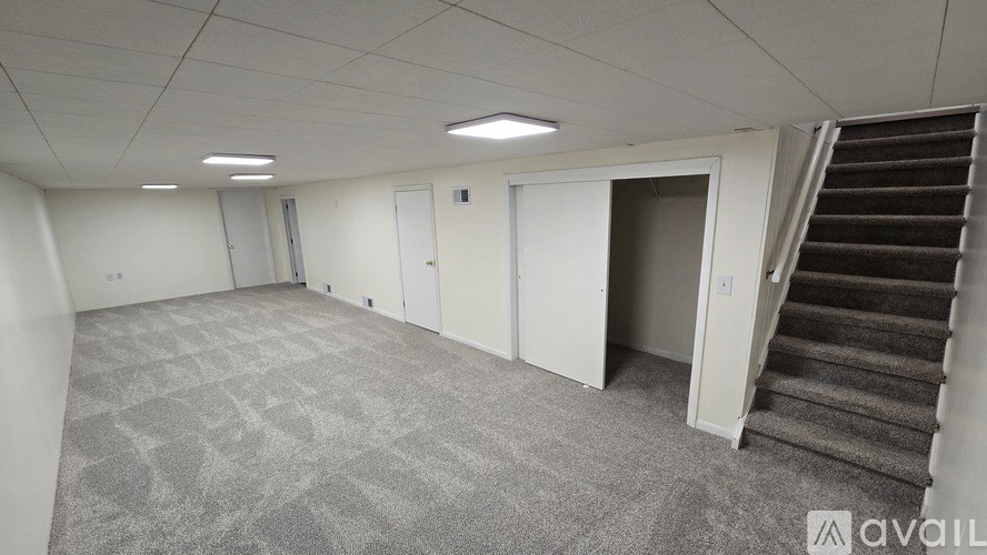 A spacious room with a staircase leading to another room.