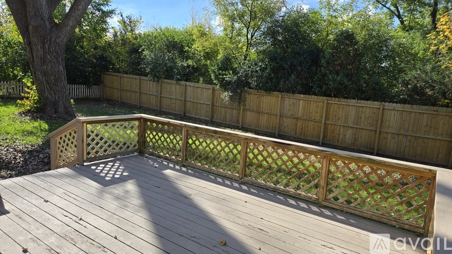 A wooden deck with a lattice fence and a tree in the background.