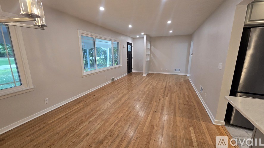 A spacious room with wooden flooring and a large window.