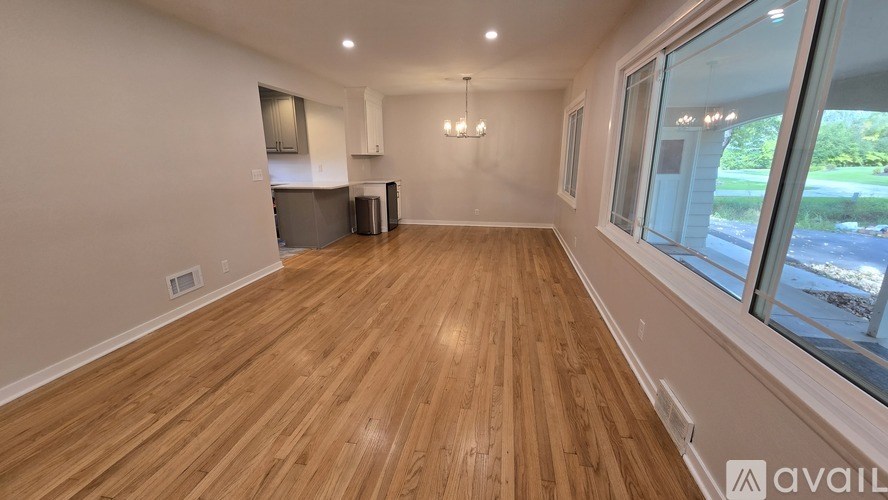 A room with wooden flooring and a large window overlooking a street.