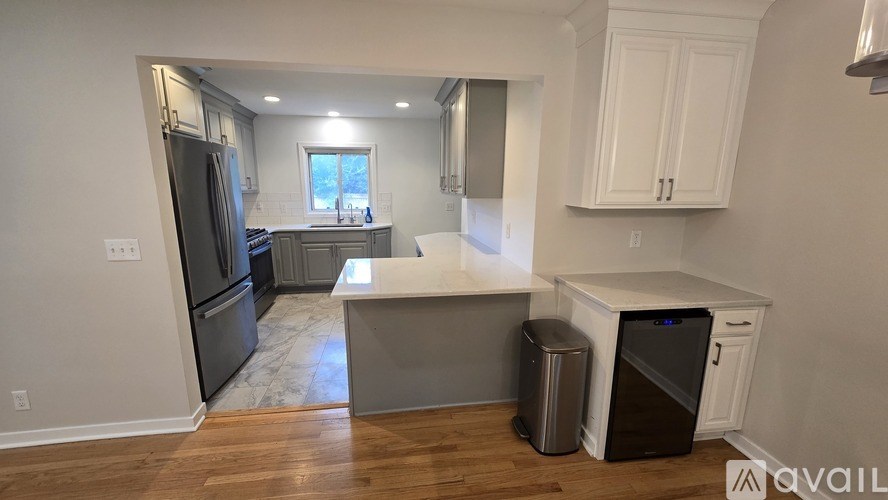 A kitchen with a refrigerator, sink, and trash can.