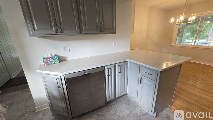 A kitchen with a white countertop and grey cabinets.