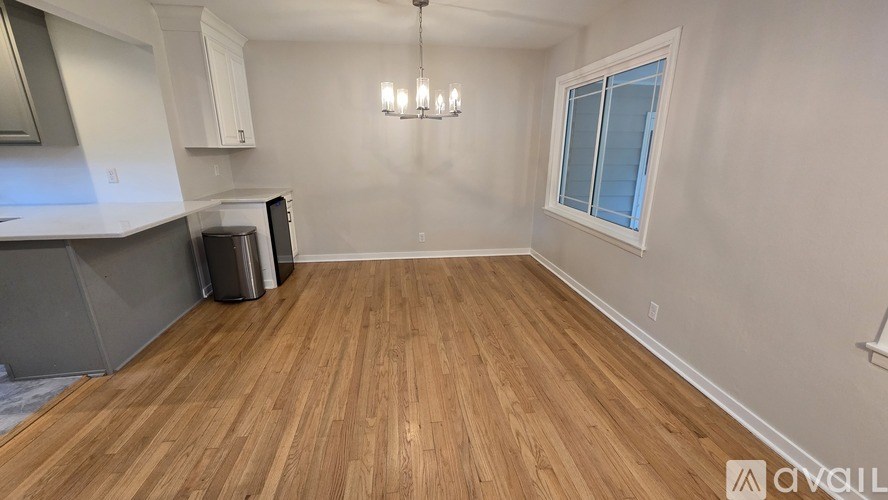 A room with wooden flooring and a window with white blinds.
