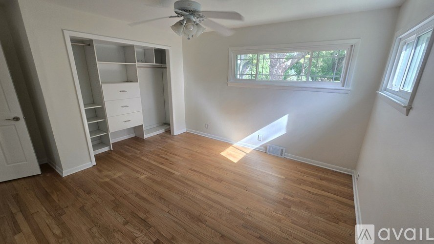 A room with a ceiling fan and a window with sunlight coming through.