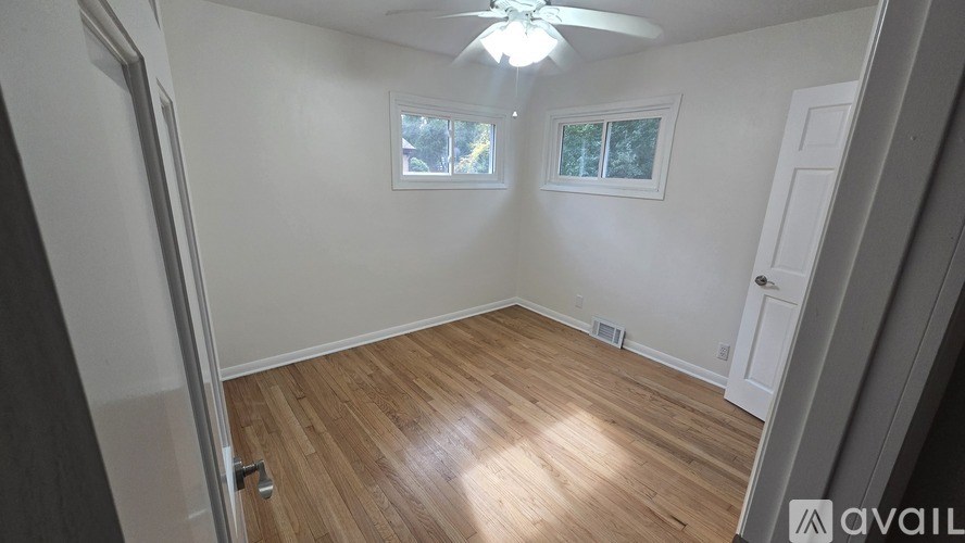 A room with a ceiling fan and wooden flooring.