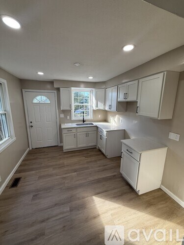 A kitchen with white cabinets and a wooden floor.
