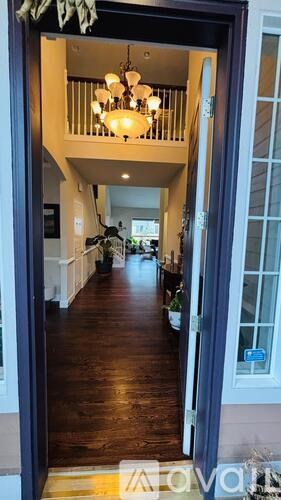 A hallway with a chandelier and a plant.