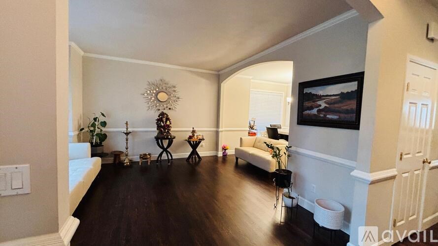 A living room with a white couch and a painting on the wall.