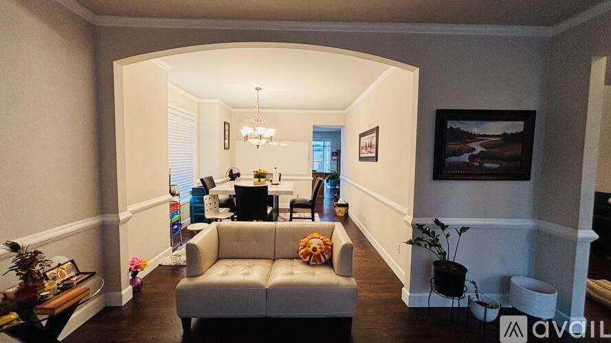 A living room with a grey couch and a chandelier.