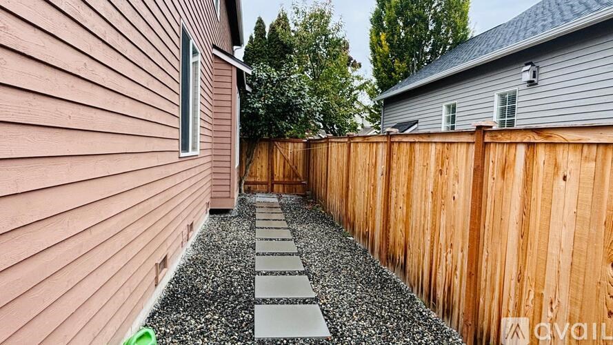 A backyard with a wooden fence and gravel path.