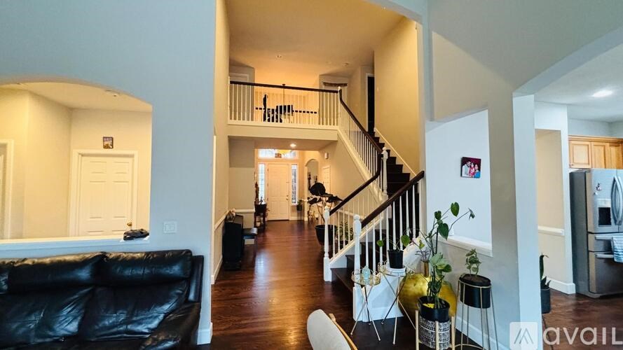 A living room with a black couch and a staircase.