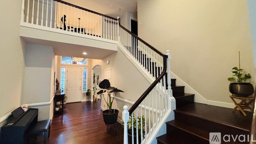 A living room with a piano and a staircase.