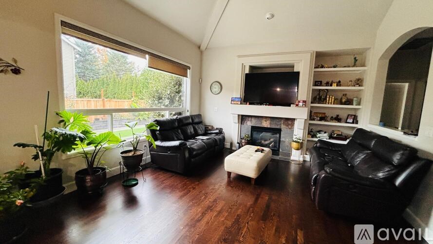 A living room with a black leather couch and a television on the wall.
