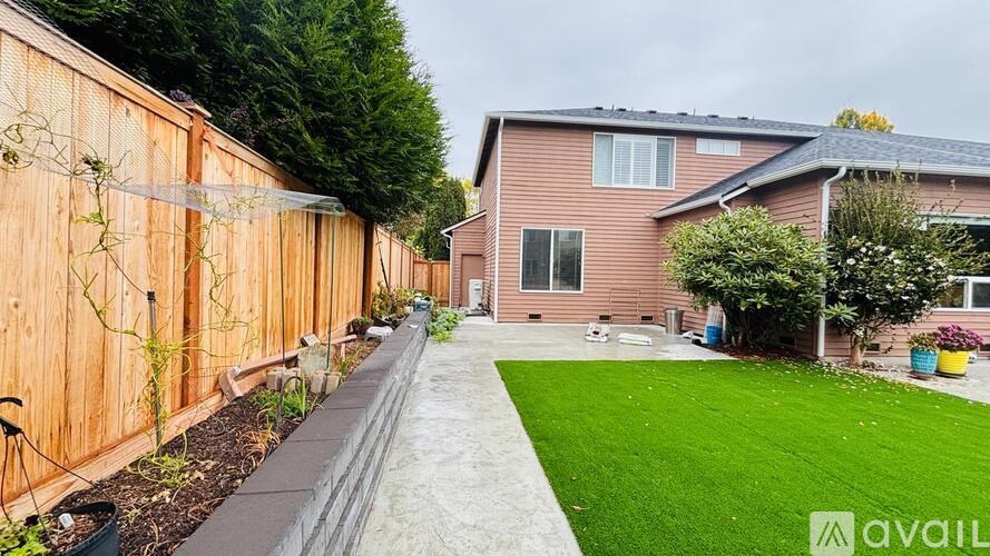 A backyard with a wooden fence and a green lawn.