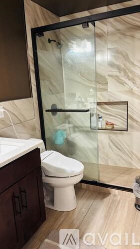 A bathroom with a toilet, sink, and a glass shower door.