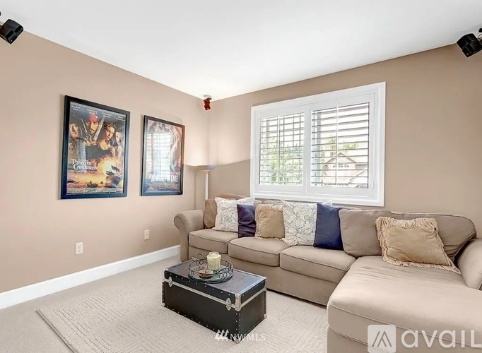 A living room with a beige couch, a coffee table, and two framed pictures on the wall.