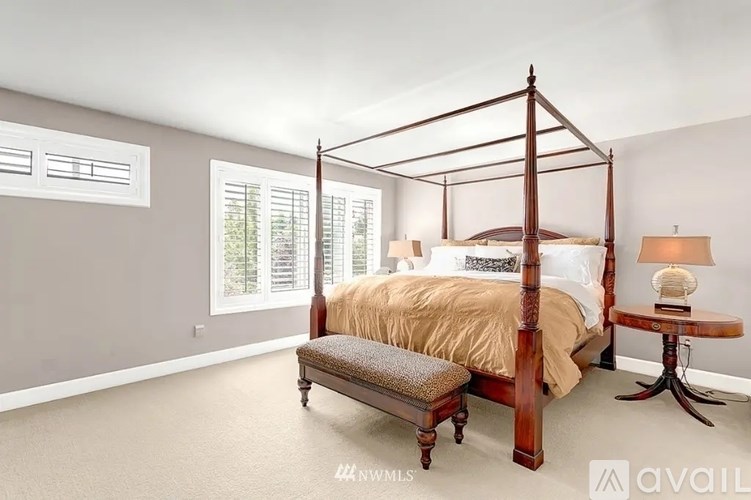 A bedroom with a four-poster bed and a bench.