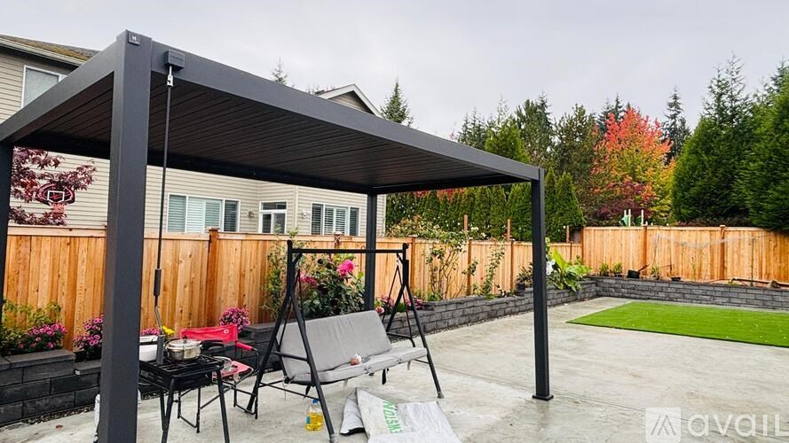 A patio with a black canopy and a grill.