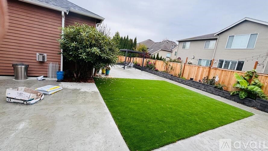 A backyard with a green lawn and a concrete patio.