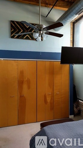 A room with a ceiling fan and a wall with a black and white patterned picture.