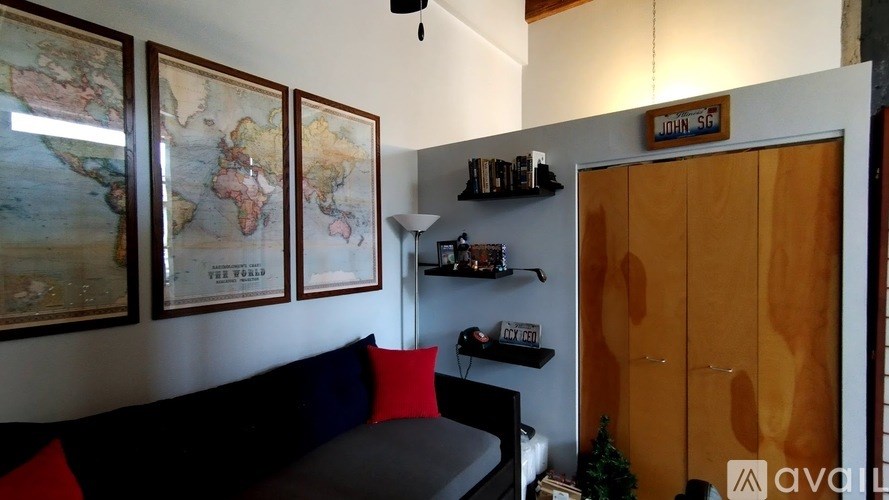 A living room with a couch, a wall with maps, and a wooden door.