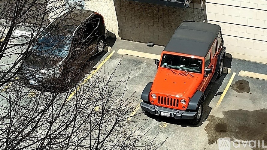 A black car is parked behind a red jeep.