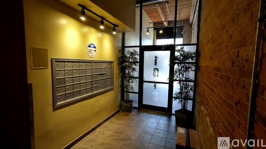 A hallway with a brick wall on the right and a mailbox on the left.