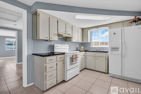 A kitchen with white appliances and beige cabinets.